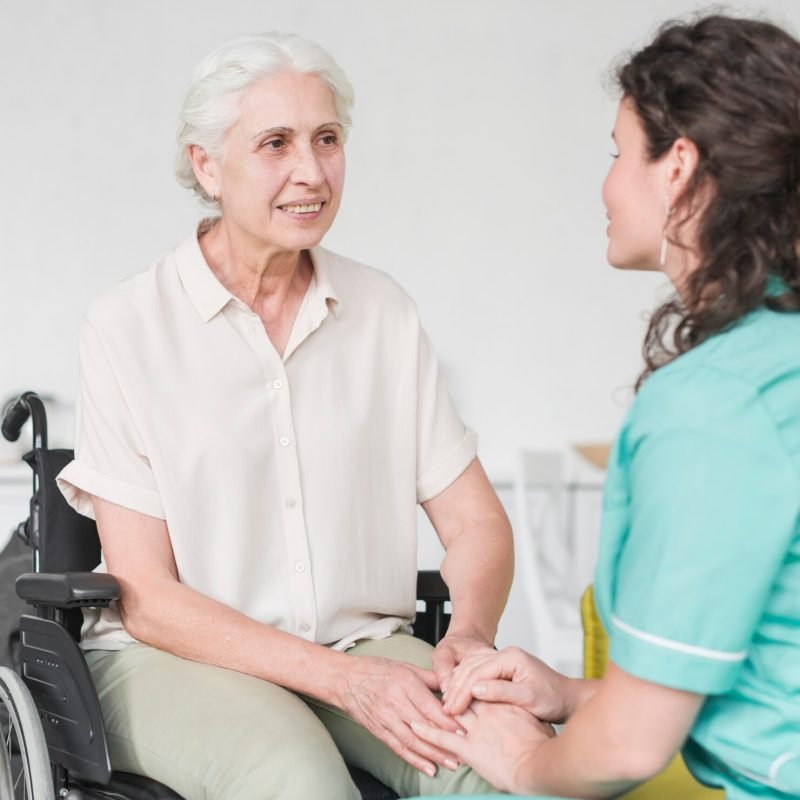 happy-disabled-nurse-sitting-wheel-chair-looking-caretaker_23-2147861529